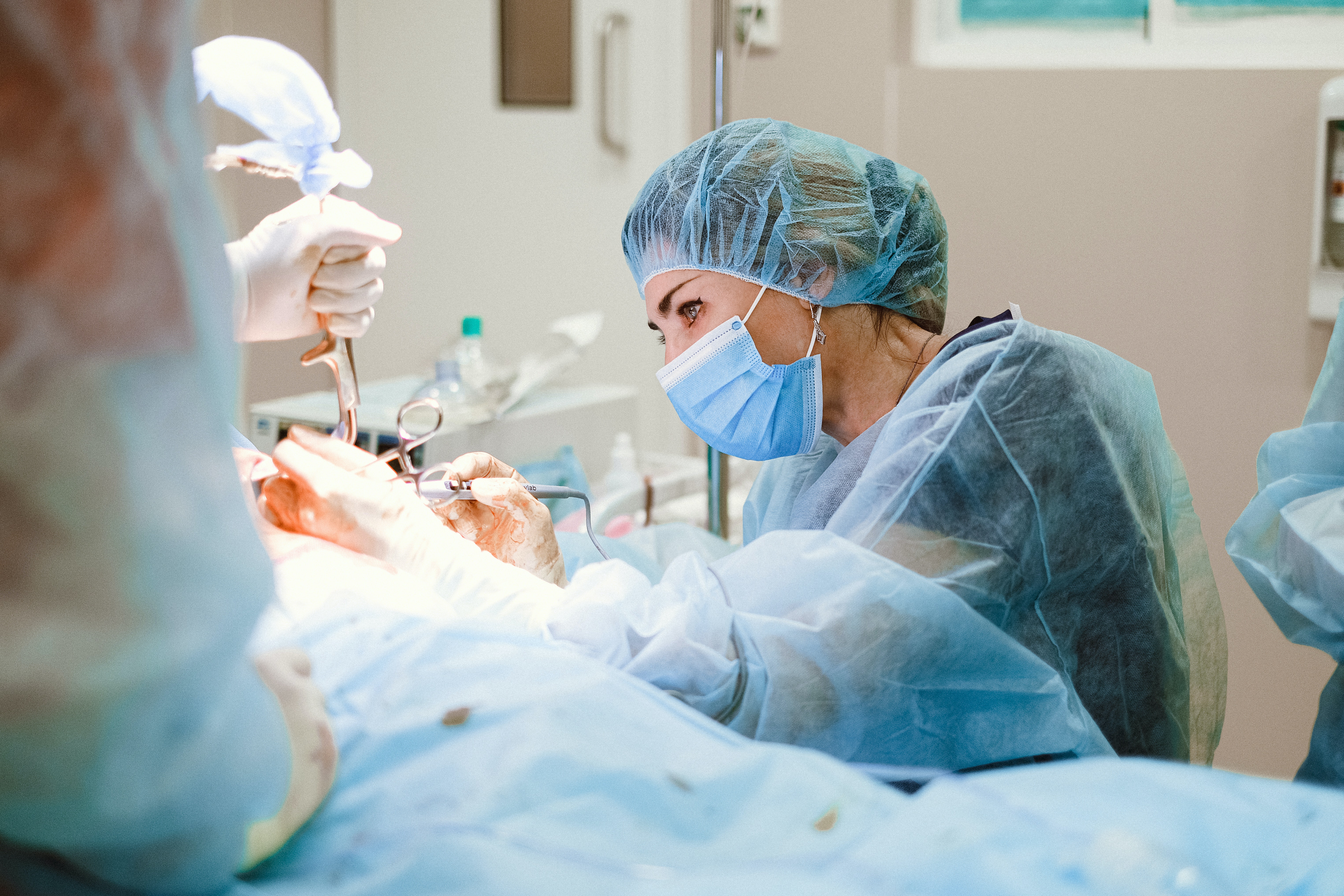 Konzentrierte Chirurgin in blauer Schutzkleidung und Maske bei einer Operation
