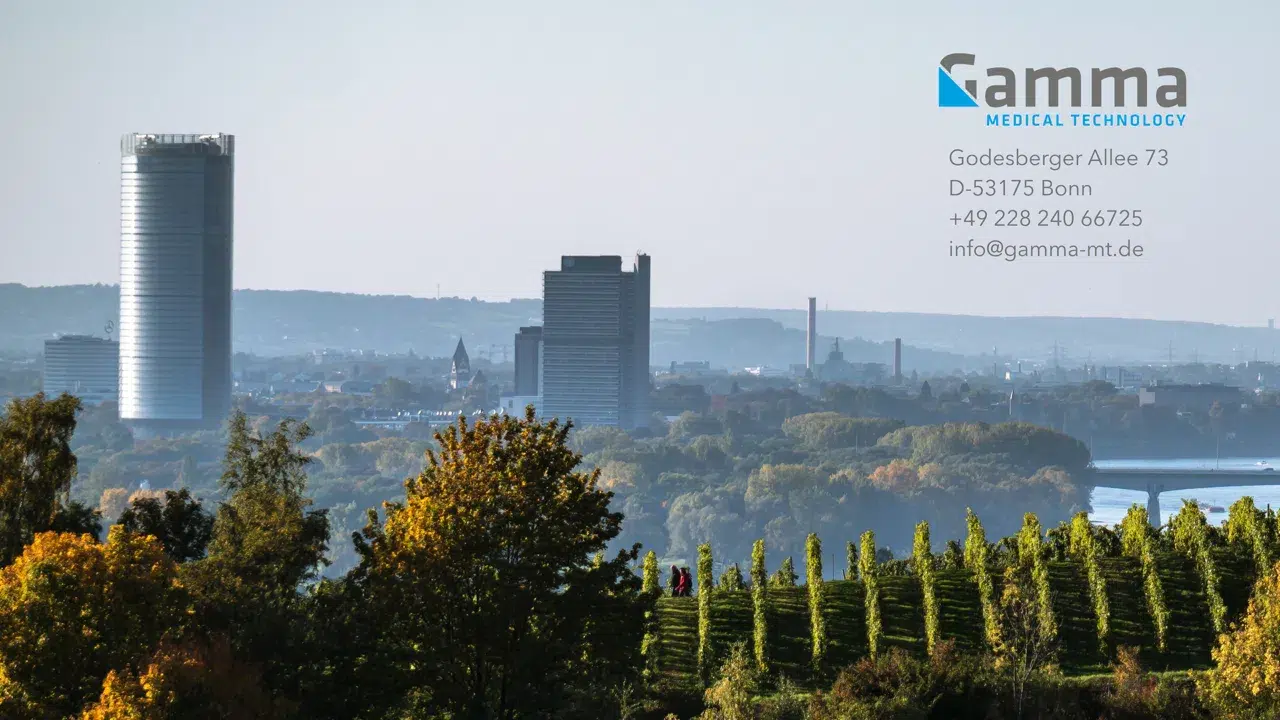 Zwei hohe Gebäude vor einer hügeligen Waldlandschaft und einem blauen Himmel